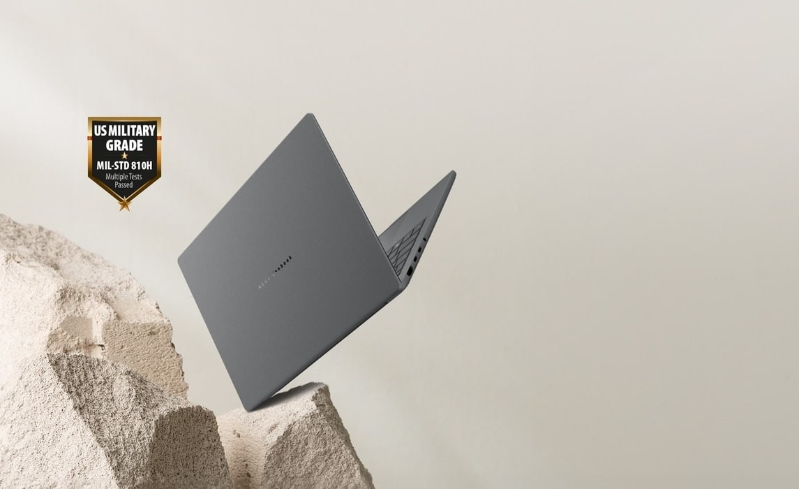 Szary laptop Zenbook A14 upadający na skałę, przy czym pokrywa jest otwarta pod kątem 80 stopni, a urządzenie jest skierowane w prawą stronę.