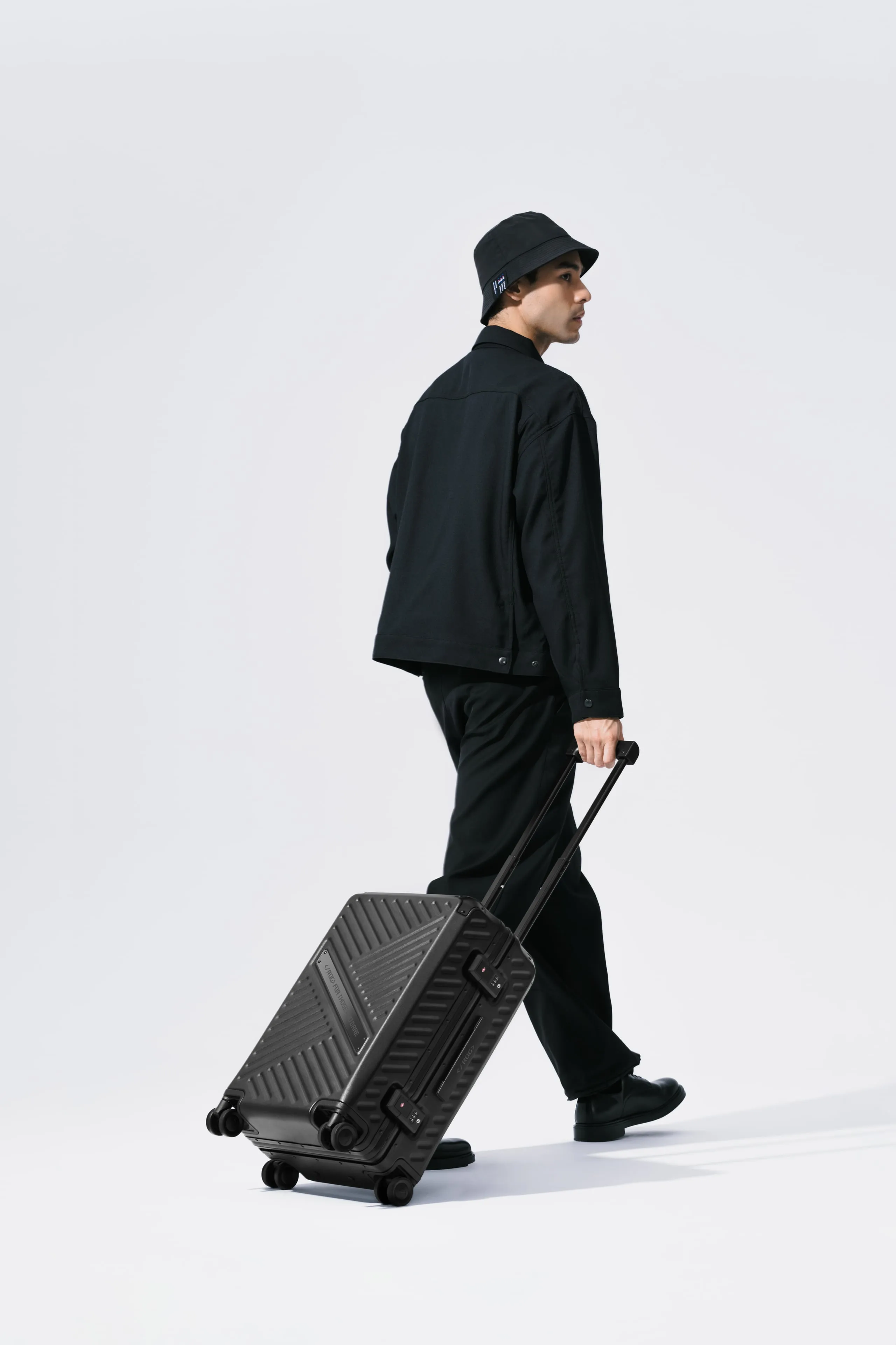Man in all black, pulling the ROG SLASH Hard Case Luggage behind him and looking over his shoulder