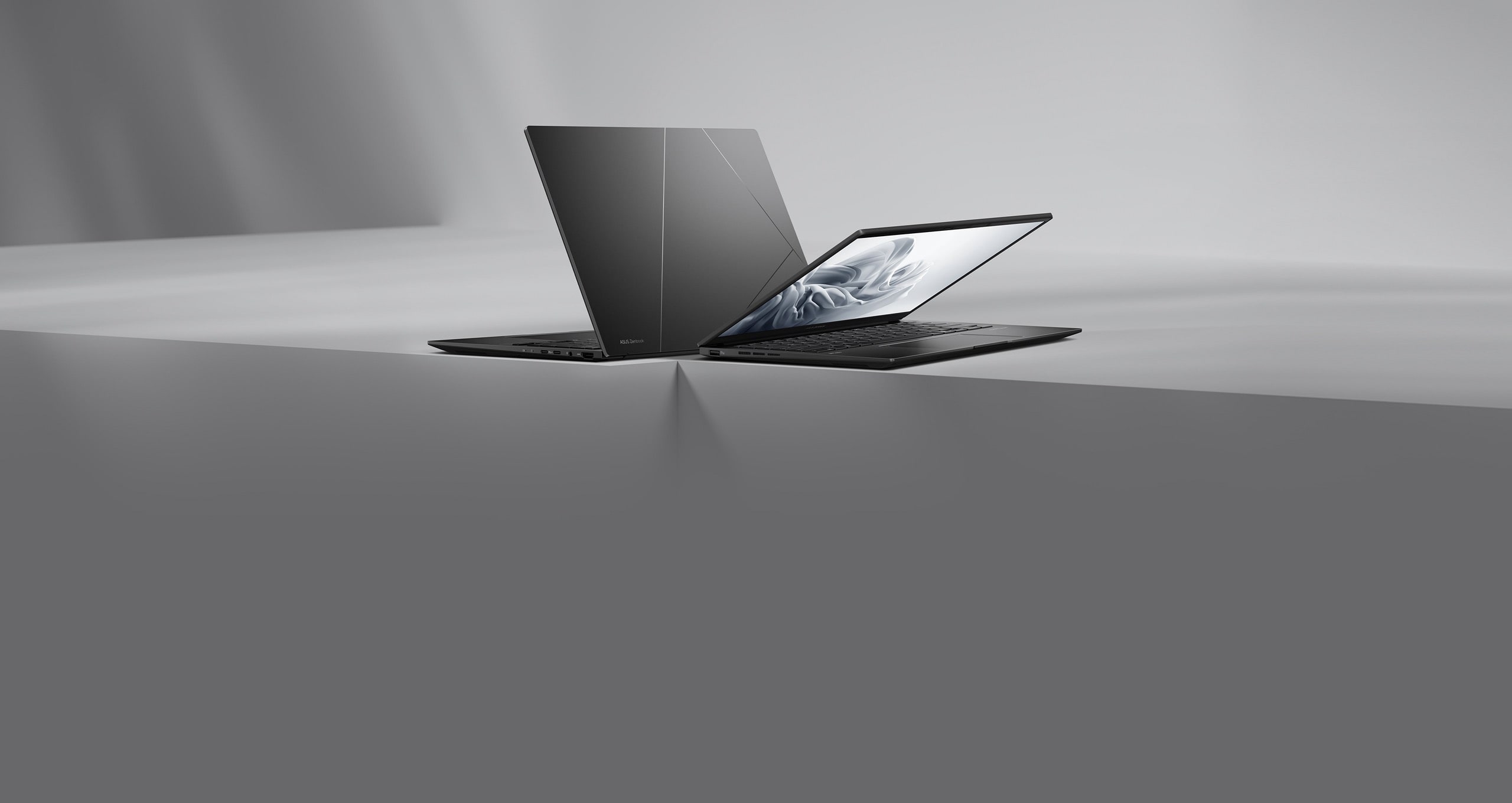 Dva notebooky Zenbook 14 OLED v barvě Jade black umístěné zády k sobě na tlumeném šedém povrchu.