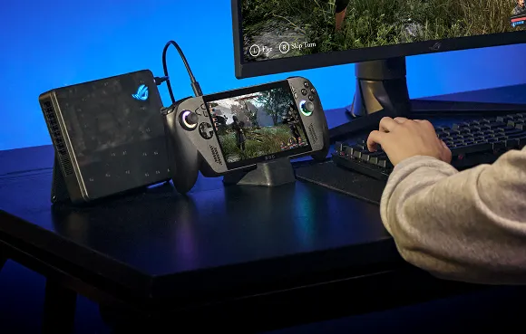 A person with an ROG Xbox Ally X, a gaming monitor, a keyboard, and a mouse at a desk, using the machine as a portable PC.