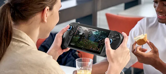 A person sitting at a table with someone else, ignoring them to play a game on the ROG Xbox Ally X.