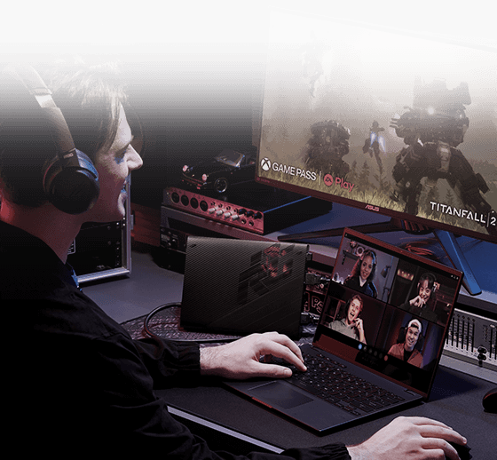 Un uomo indossa delle cuffie e utilizza un laptop su cui è visualizzata una videochiamata, mentre sullo sfondo un monitor mostra il gioco Titanfall.