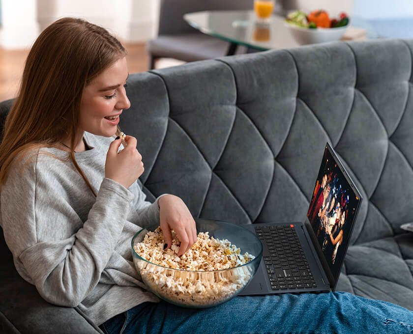 A woman is watching streaming video with popcorn.