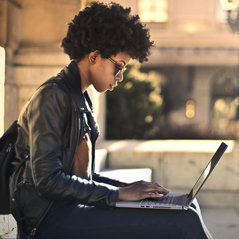 a young woman sitting on stairs outdoors using ASUS ProArt StudioBook 17 to create digital content
