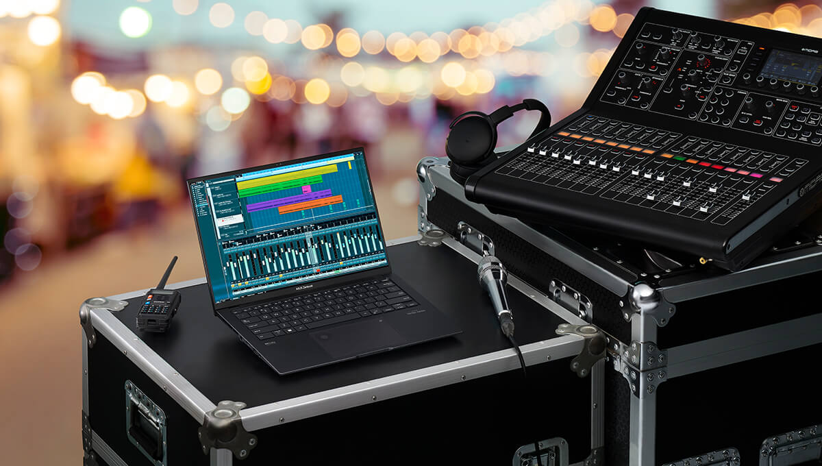 Zenbook Pro 14 OLED on a sound engineer’s workstation during an outdoor event, with a sound console and headphones lying on the crate next to the laptop