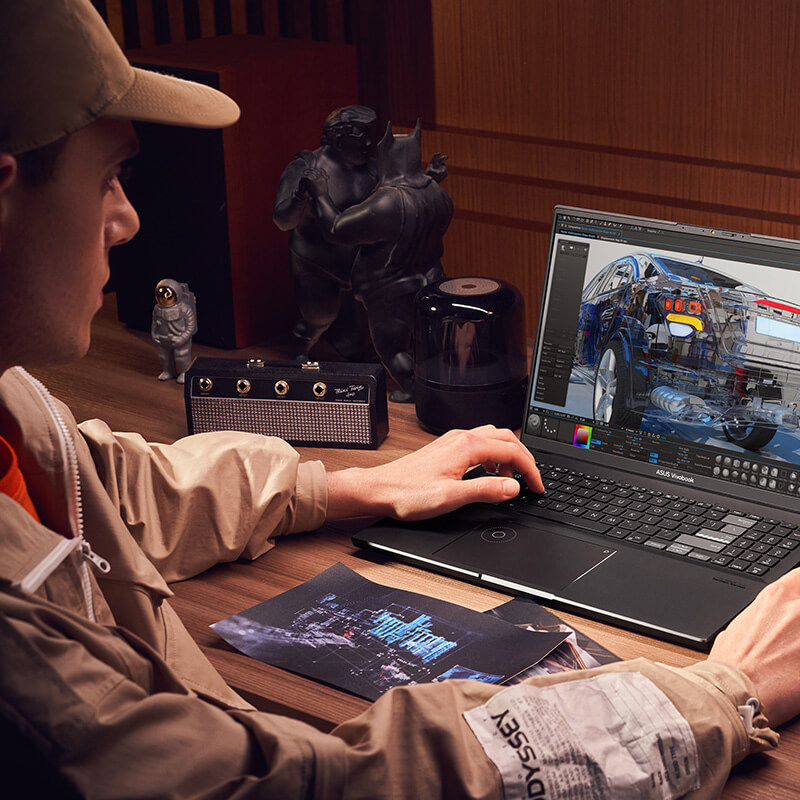 a young graphic designer working on an image featuring a car at his work desk, with various accessories and drawings on the desk, using Vivobook Pro 16X OLED creator laptop