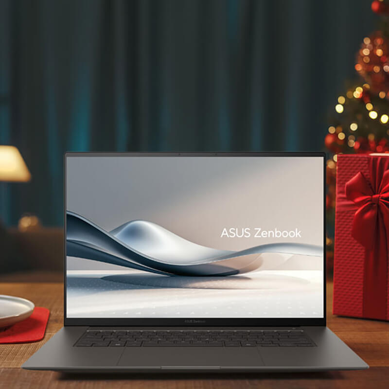 An ASUS Zenbook is placed on a wooden table with holiday decorations around it and in the background.