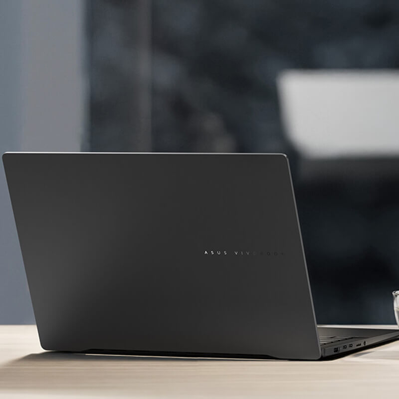 An ASUS Vivobook S 14 laptop on a desk, with a cup of coffee next to it