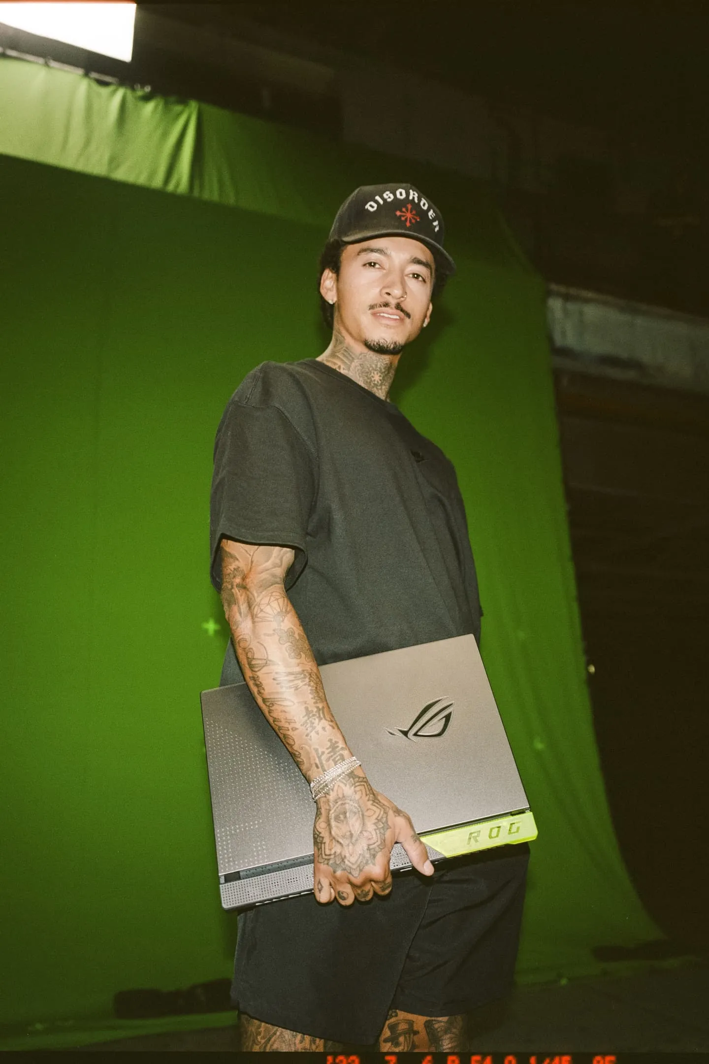 Nyjah Huston holding a ROG Strix G15 laptop, standing in front of a green screen.