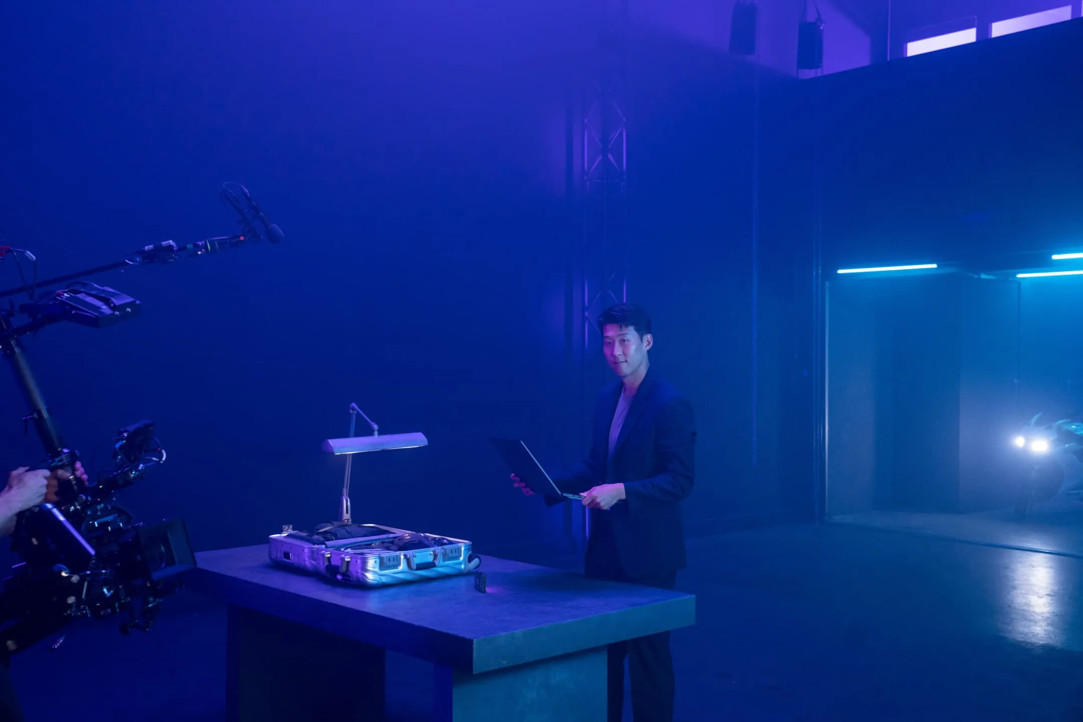 Son Heung-min on set, holding a Flow X16 laptop and standing in front of a table.