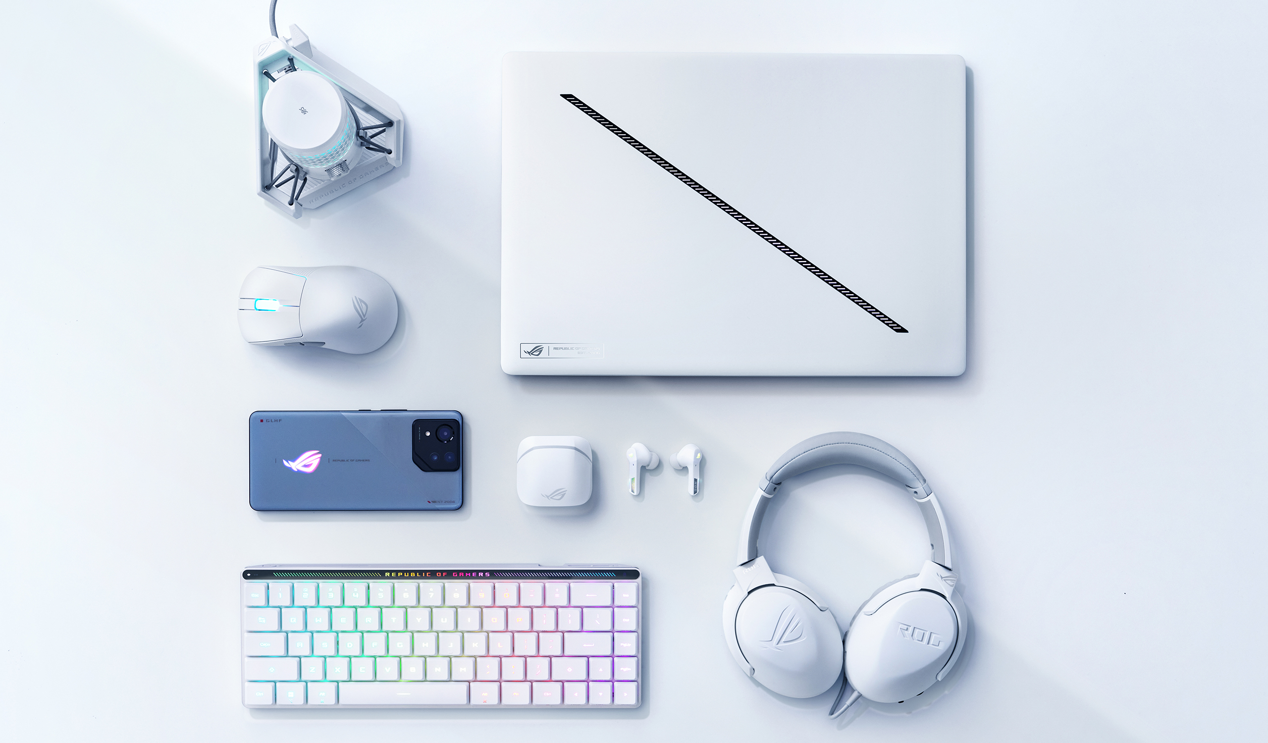 Un Zephyrus G16 Platinum White, rangé à côté d'une souris ROG, d'un étui de transport et de son adaptateur d'alimentation.