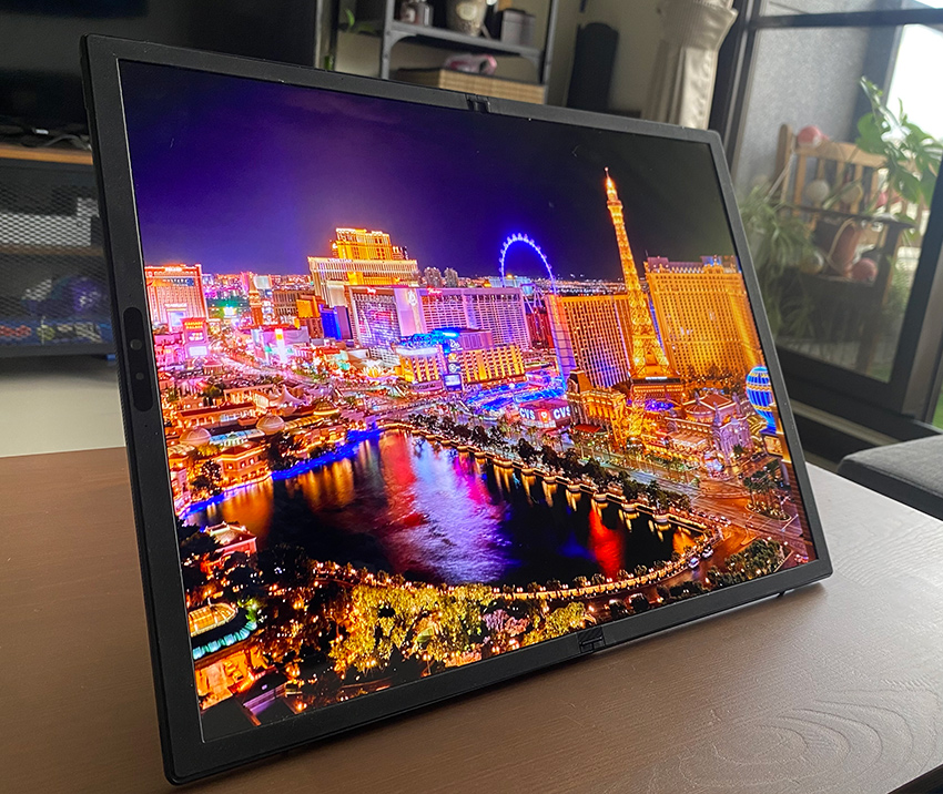 Fully unfolded ASUS Zenbook 17 Fold OLED displaying a colorful scenery of Las Vegas at night, propped on the leather kickstand on my living room coffee table