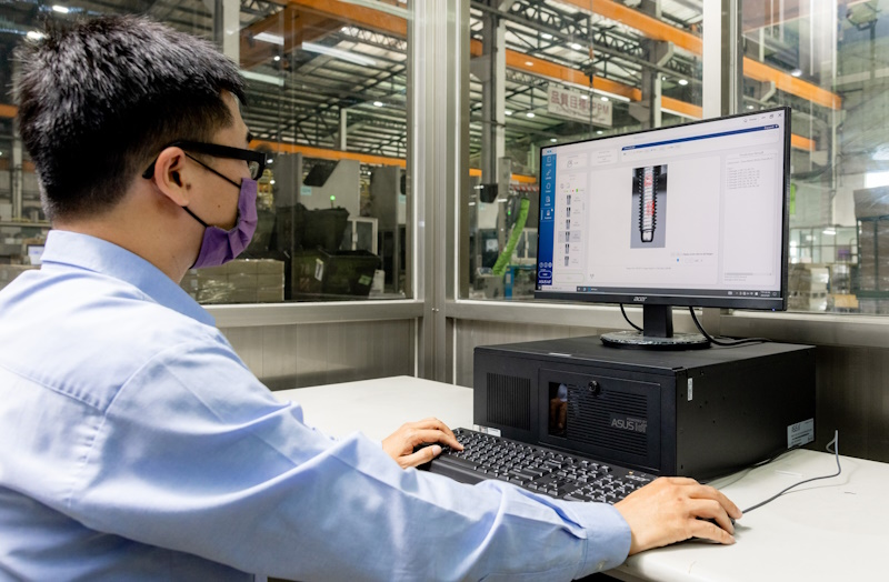 Engineer reviews technical designs on a computer in a manufacturing facility.