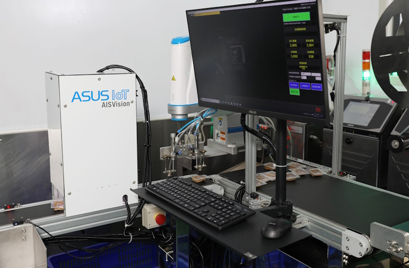A robotic assembly line featuring an ASUS IoT system. A touchscreen displays data related to the automated manufacturing process.