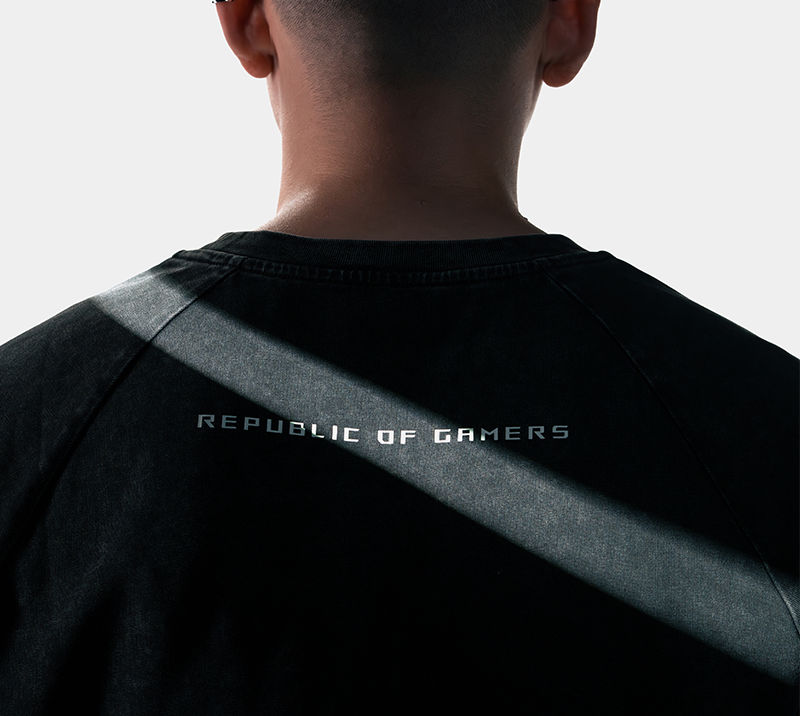 The front view of a woman wearing the ROG Ombre T-shirt in black version angled from the right and held the skateboard