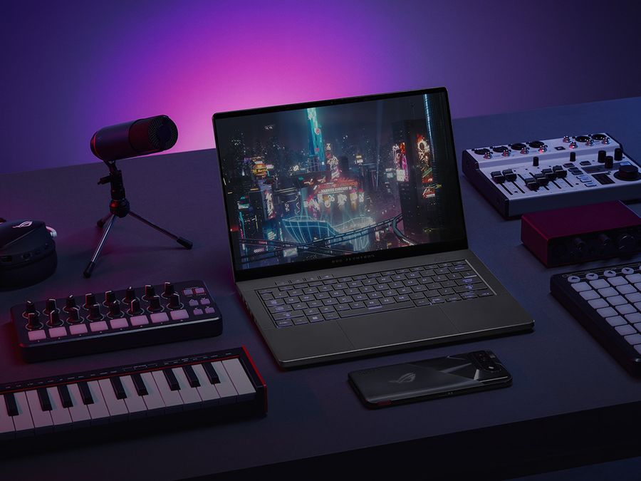 An ROG Zephyrus G14 sits on table with the lid open and a cyberpunk scene on screen, flanked by digital music production equipment, and ROG Phone, and ROG Carnyx microphone, and an ROG headset.