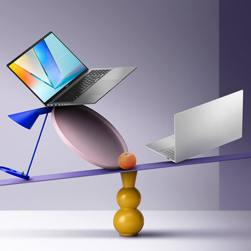 Two ASUS Vivobook S16 laptops on a colorful seesaw background