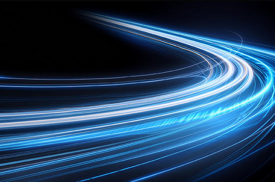 Curved streaks of glowing blue and white light trails on a dark background, symbolizing speed and motion.