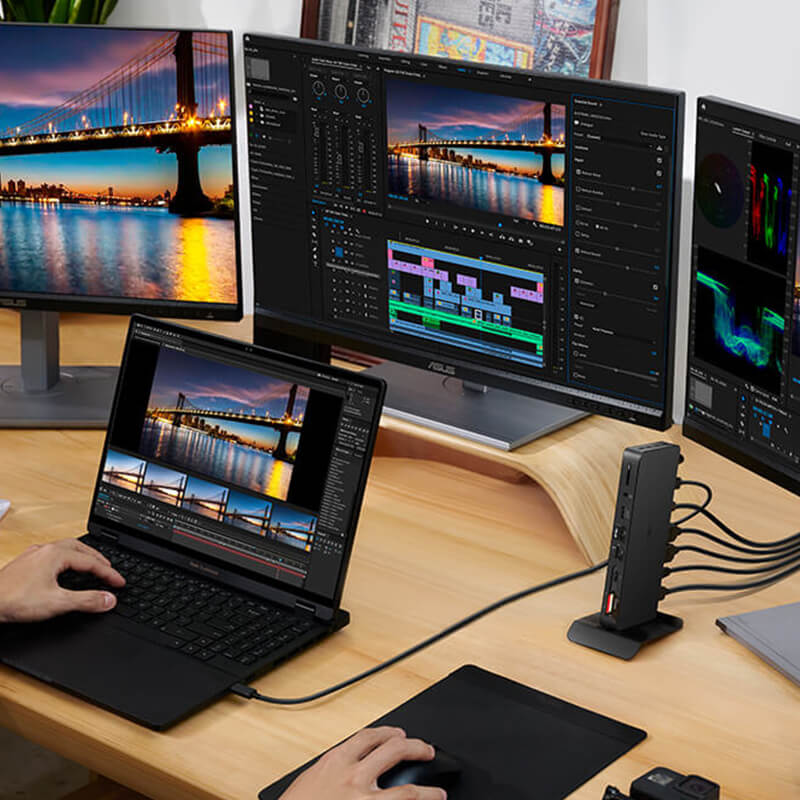 A laptop is put on the table with three monitors connected in front of it. Some of the screens show a stunning night view of the bridge, while others display video editing of the same bridge. There’s a Zenfone next to the laptop.