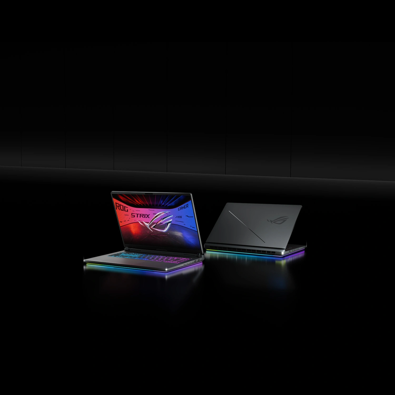 Two ROG Strix laptops on a table with the lids partially opened.