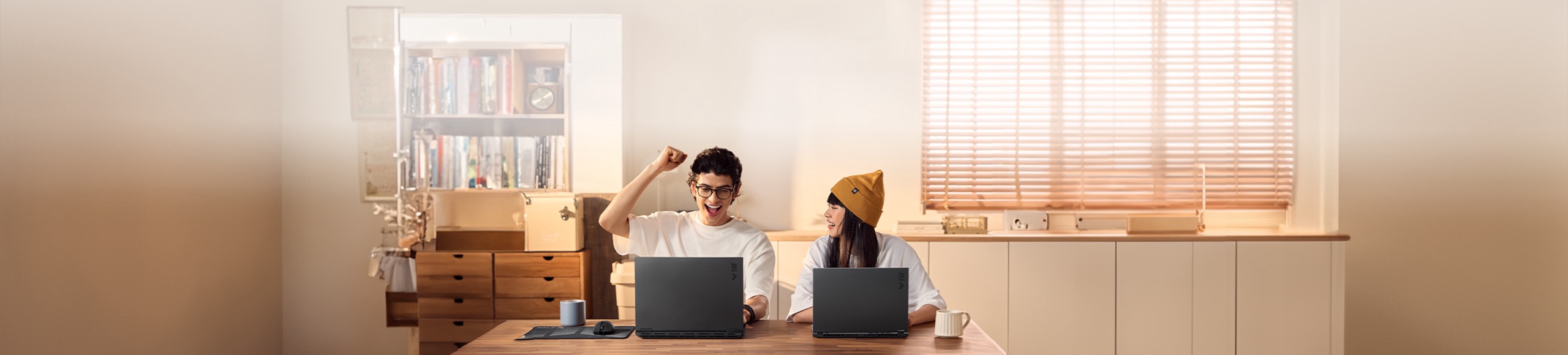 Two friends using TUF Gaming laptops together happily. 