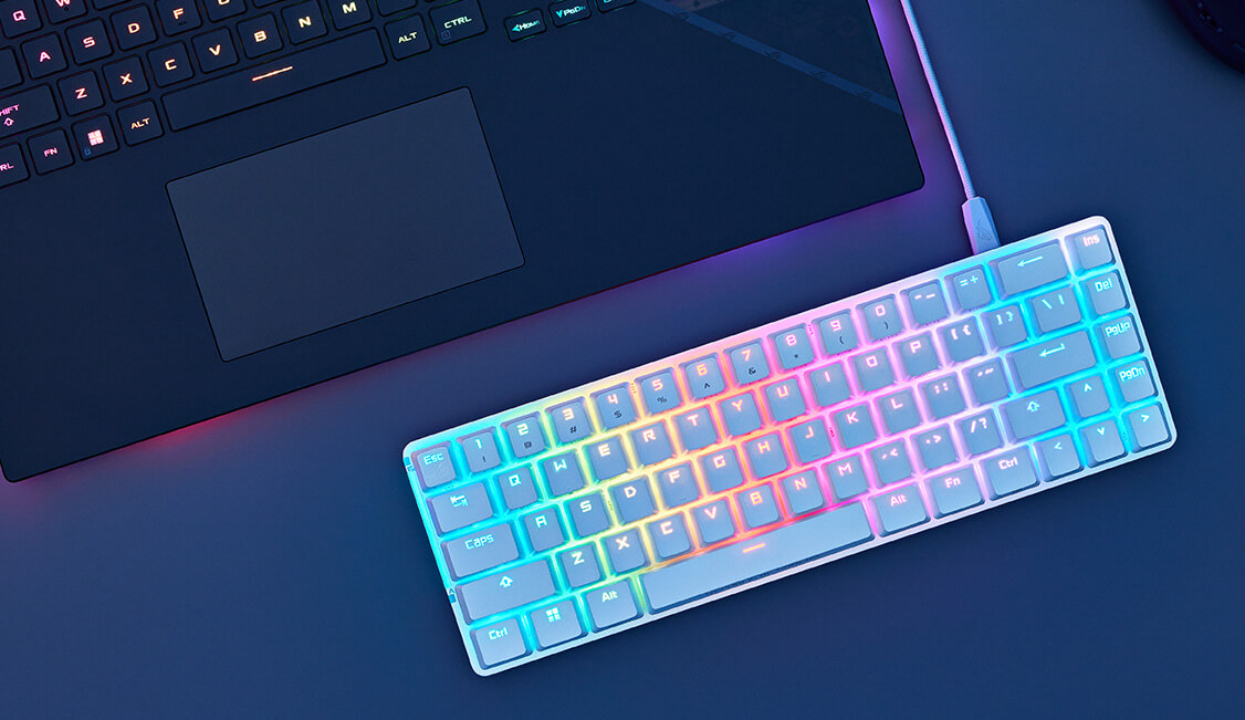 ROG Falchion Ace màu trắng bên cạnh laptop, thể hiện đèn RGB