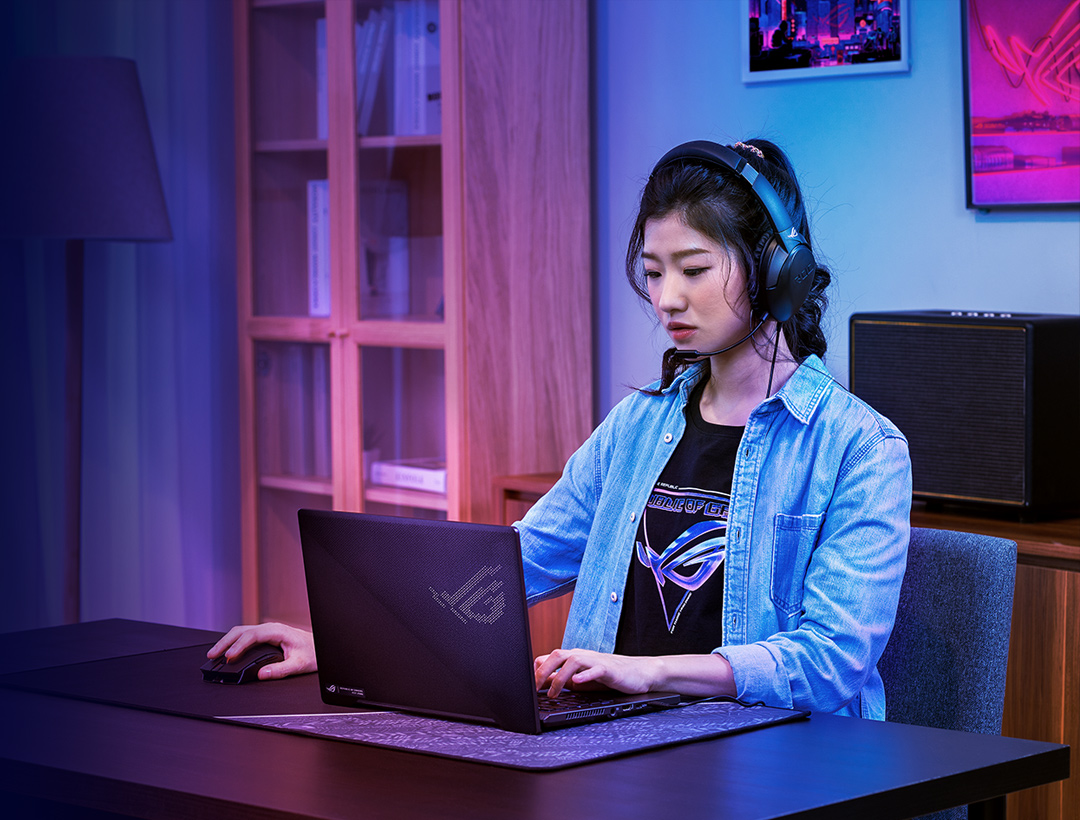 A women using the ROG laptop with ROG Strix Go Core headset
