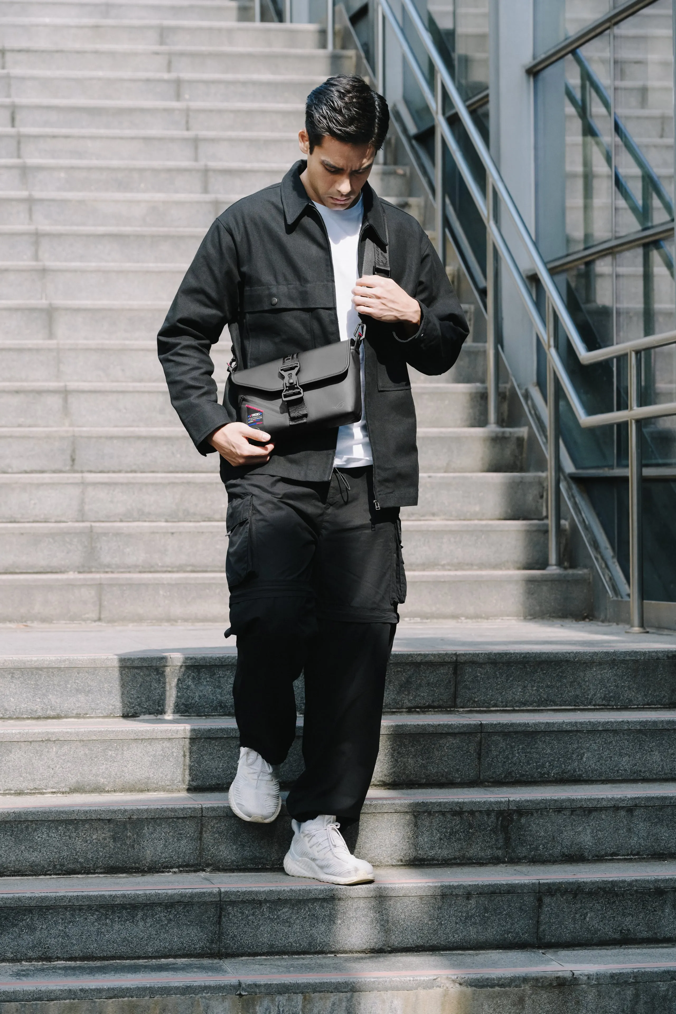 Man walking down a staircase with the ROG SLASH Sling Bag 2.0 over his front