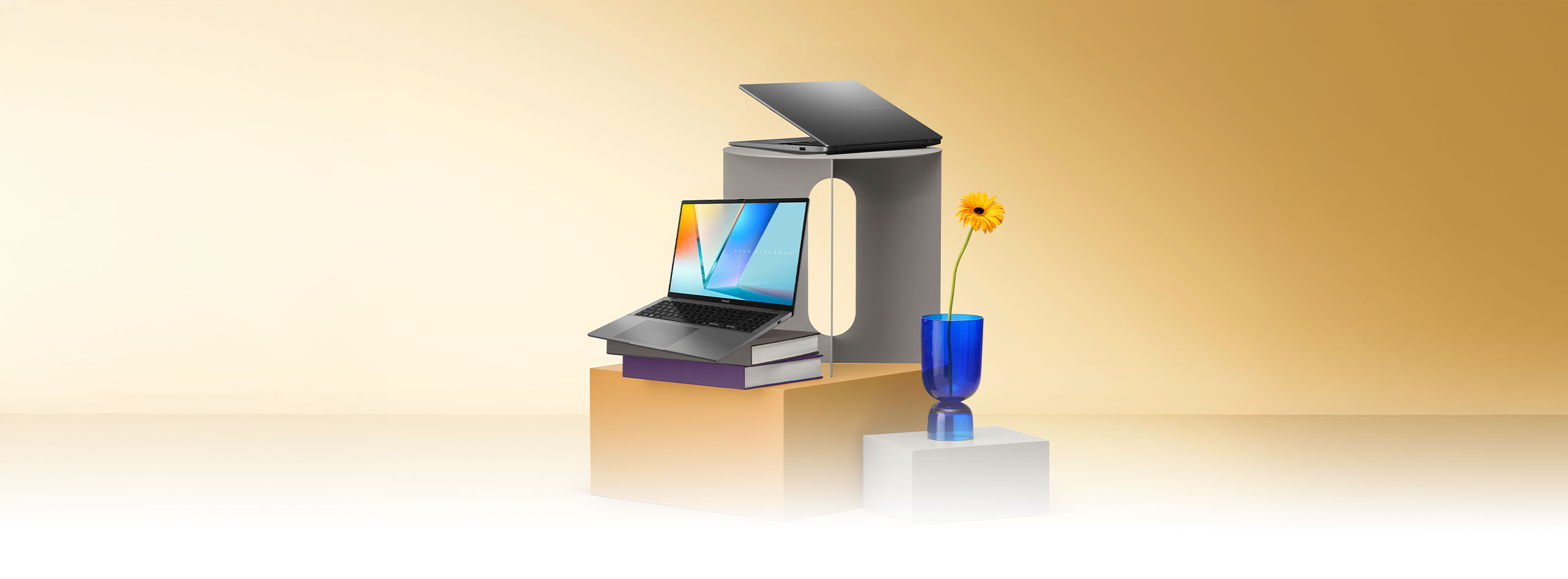Two open laptops, one grey and one silver, appear angled in front of overlapping yellow and blue rectangular and circular shapes.