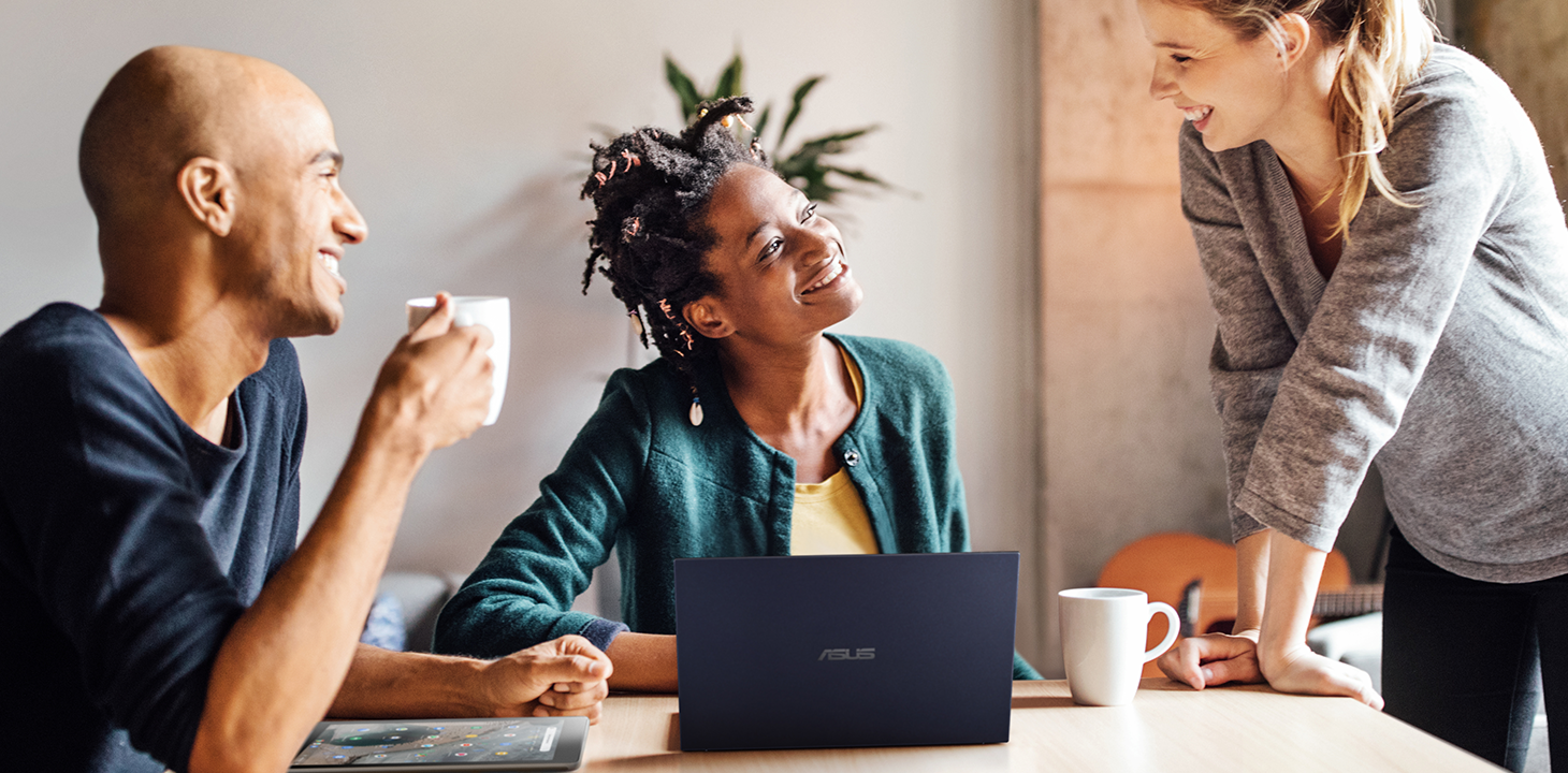 Trois créatifs discutent joyeusement dans un bureau.