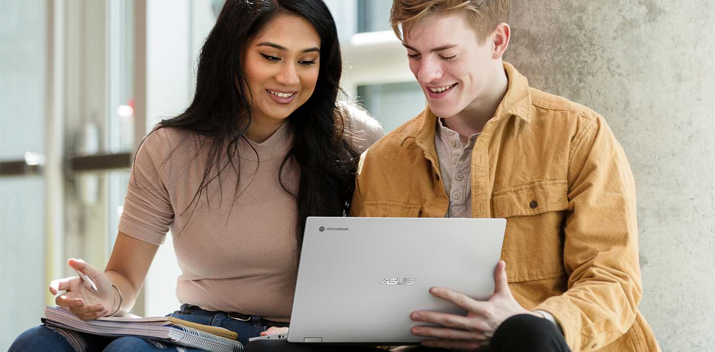 Kaksi yliopisto-opiskelijaa istuu ulkona ja työskentelee yhdessä ASUS Chromebookilla.