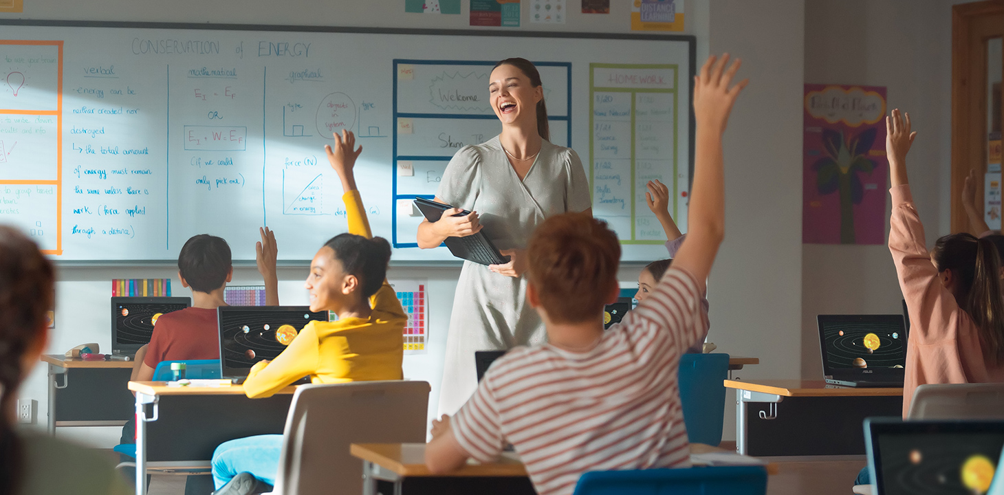 Un enseignant entouré d'élèves du primaire et du secondaire utilisant des ordinateurs portables ASUS BR1100 dans la salle de classe.