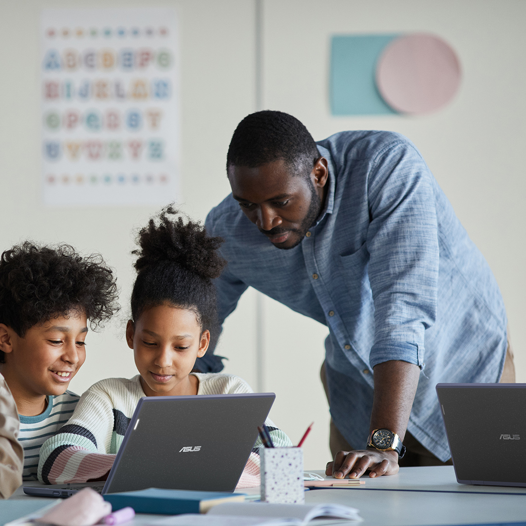 Een lerares kijkt naar de ASUS ExpertBook B3 Flip om op afstand les te geven vanuit haar kamer, terwijl een hand achter haar op een whiteboard schrijft.