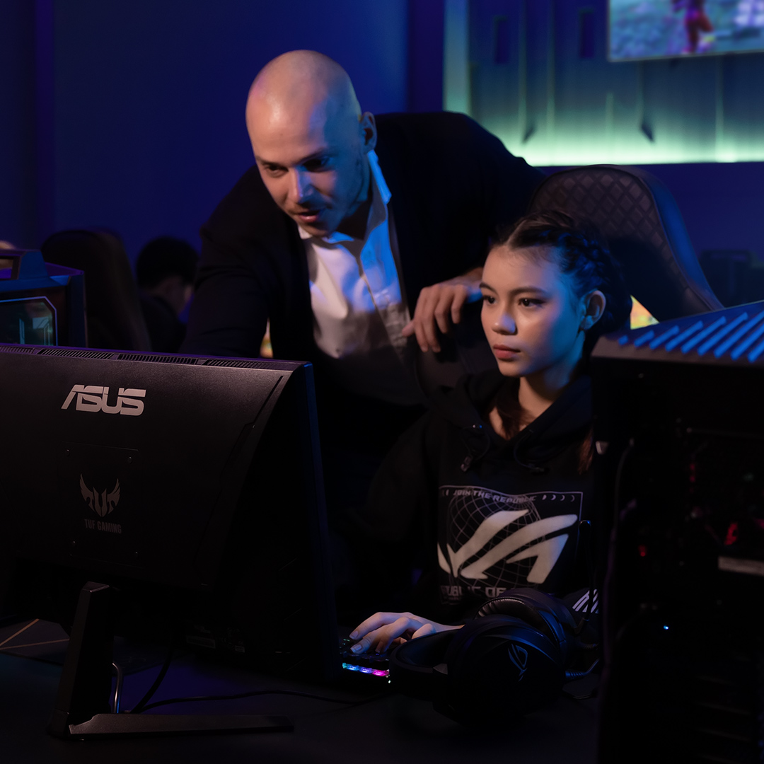 A teacher is teaching a female student with a ROG desktop and ASUS monitor.
