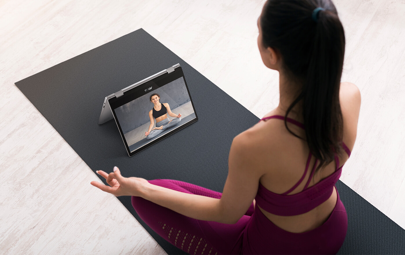 Eine Frau, die Yoga macht und dabei nahtlos ein Yoga-Video mit einem Tablet abspielt.