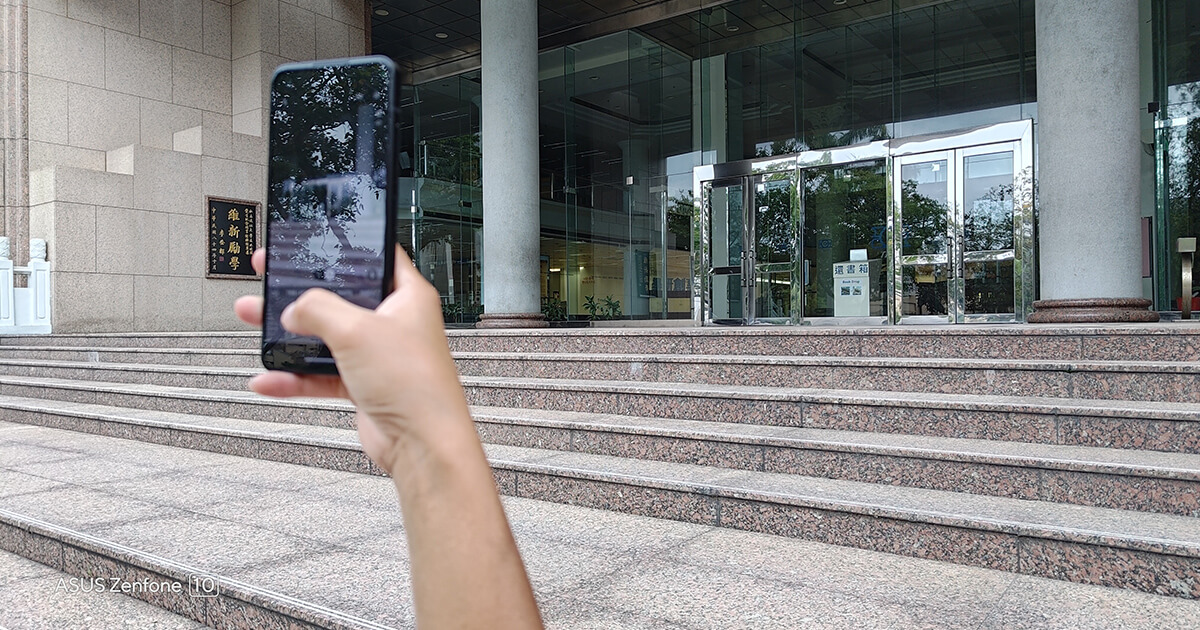 a person taking pictures with Zenfone 10 while holding the phone with one hand and walking on stairs.