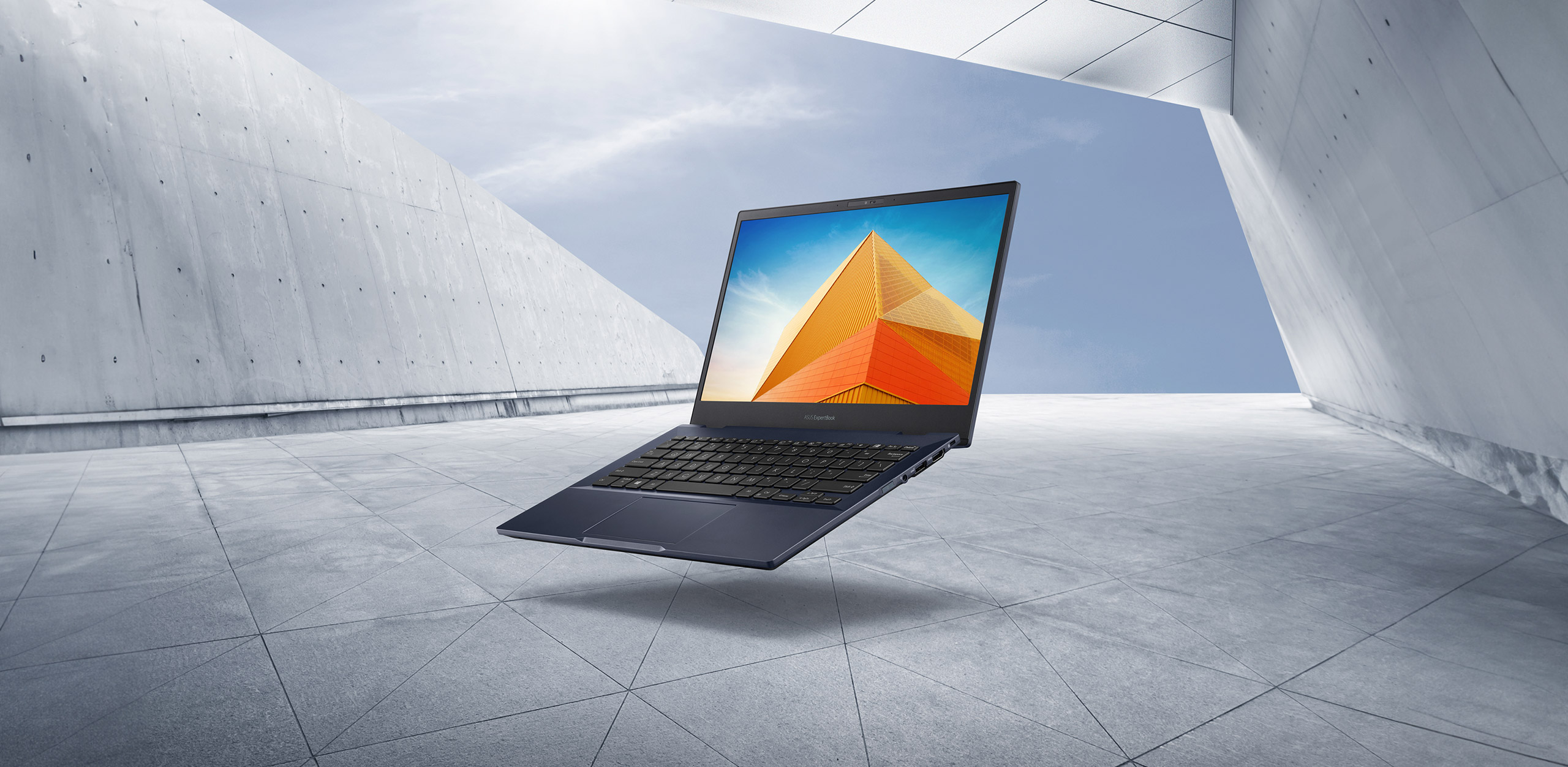 ASUS ExpertBook B5, sur fond de ciel bleu et d'architecture minimaliste.