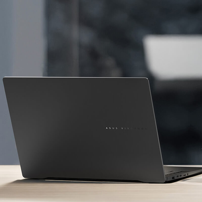 An ASUS Vivobook S 14 laptop on a desk, with a cup of coffee next to it