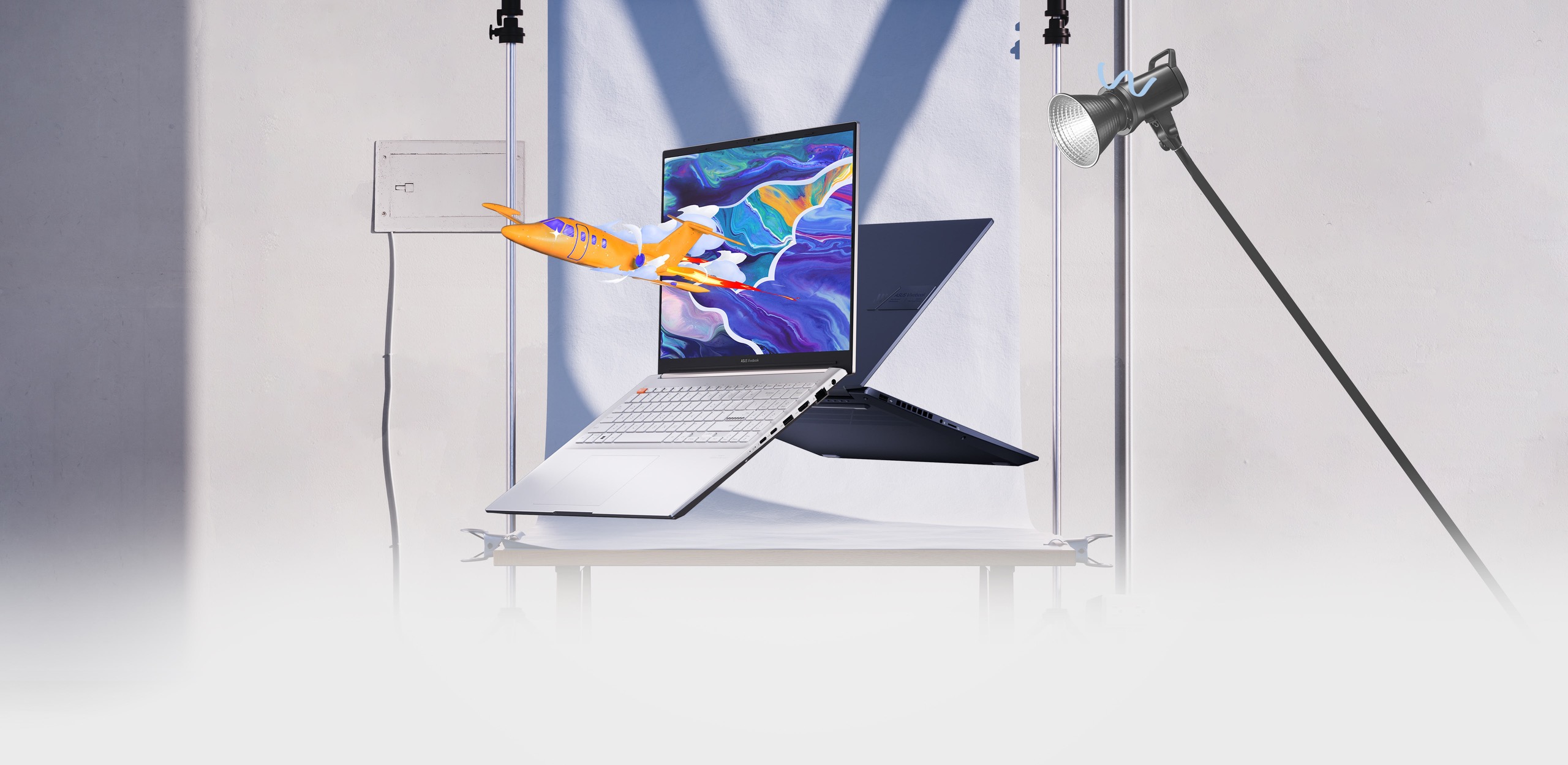   兩台 Vivobook Pro 16 OLED 筆電的前、後視圖，其中一台顯示飛機從螢幕上的彩色圖形中躍出