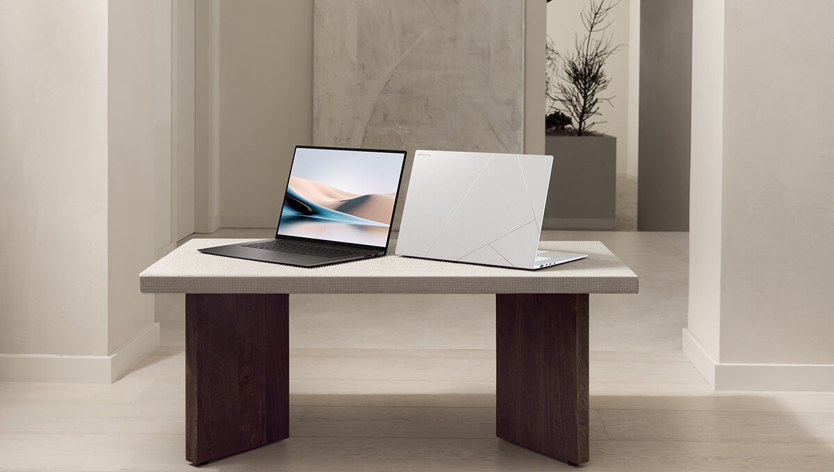 two ASUS Zenbook S 16 laptops in Scandinavian White and Zumaia Gray colors sitting opened on a stone table inside of a modern, bright room