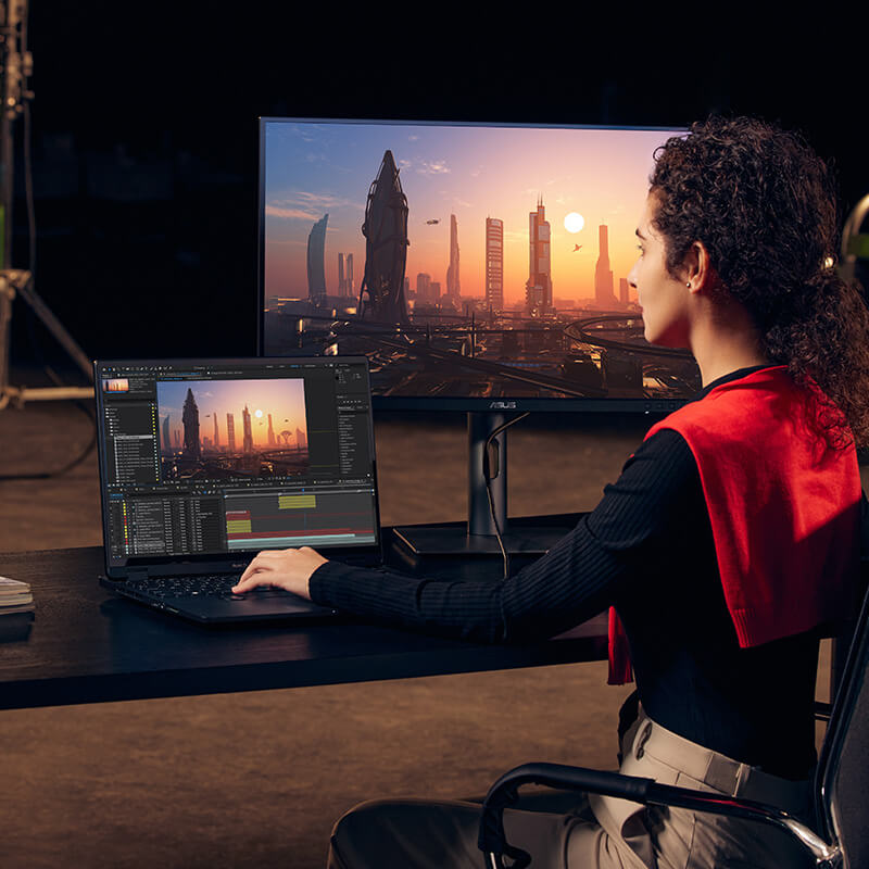 a female content creator editing a video in her studio using a ProArt Studiobook creator laptop and a ProArt monitor