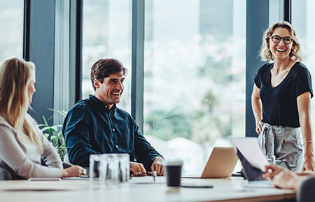 Three team members collaborating, smiling warmly as they engage in discussion.