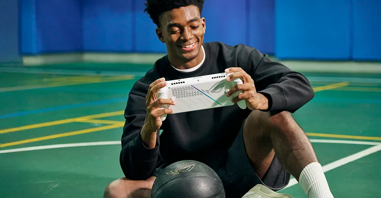 A person sitting on an astroturf field playing with an ROG Xbox Ally.