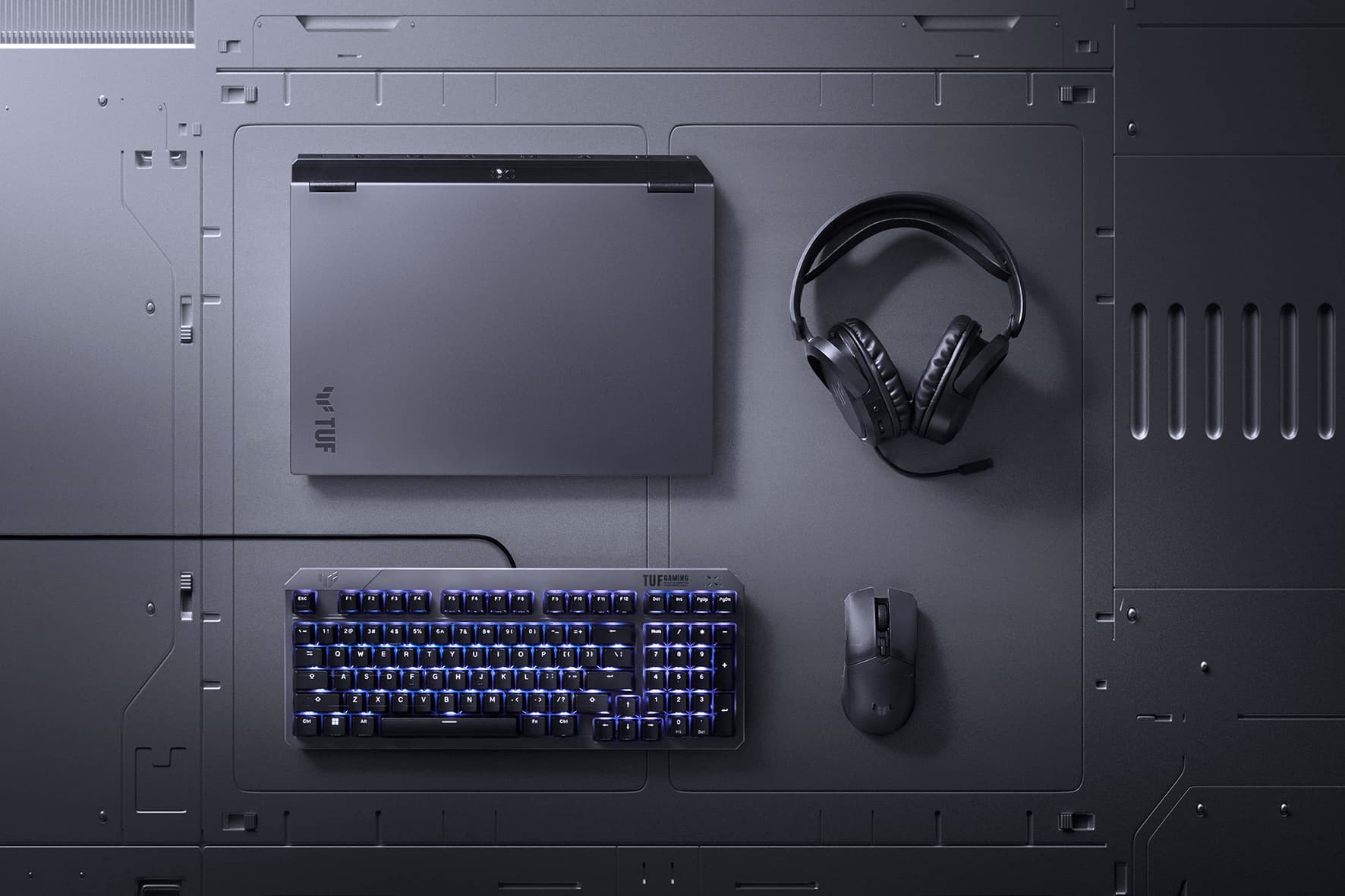A TUF Gaming F16, headset, mouse, and keyboard arranged on a metallic background.