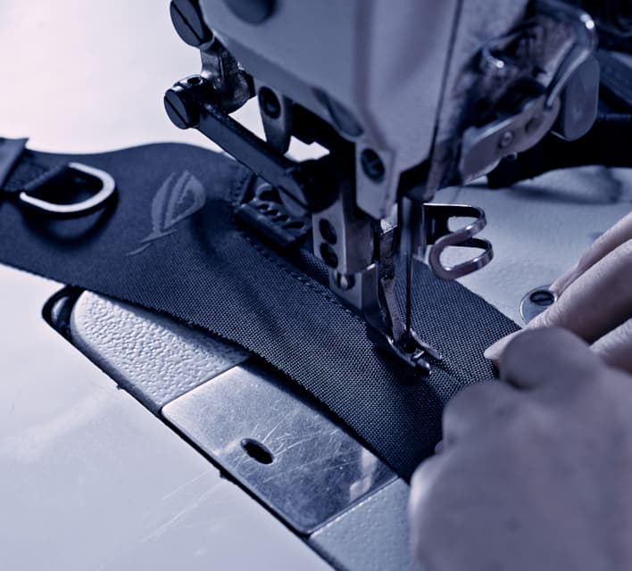 A shot of a sowing machine sowing thread into a piece of fabric with the ROG logo on it.