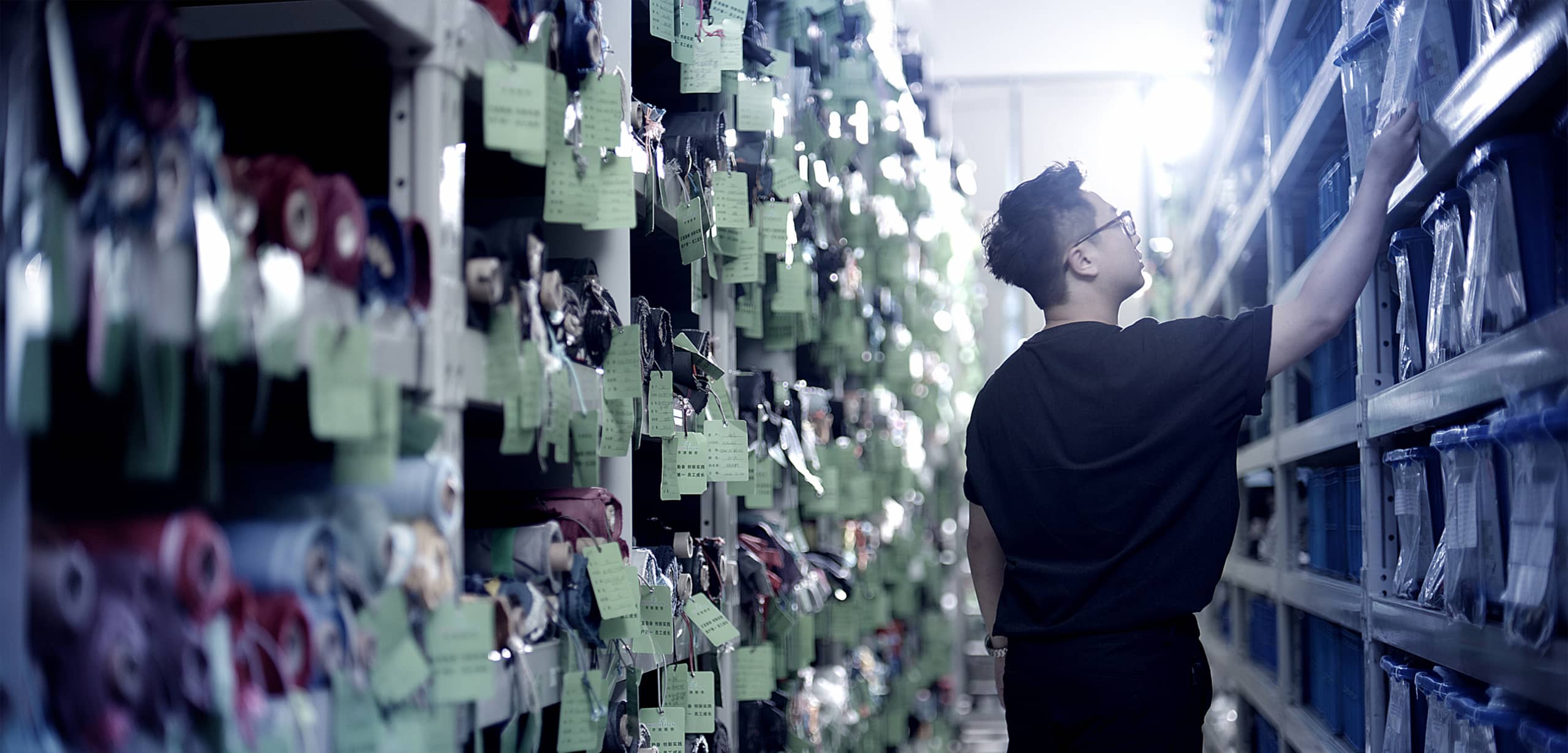 A man picking fabric in a room full of different cloths and fabrics.
