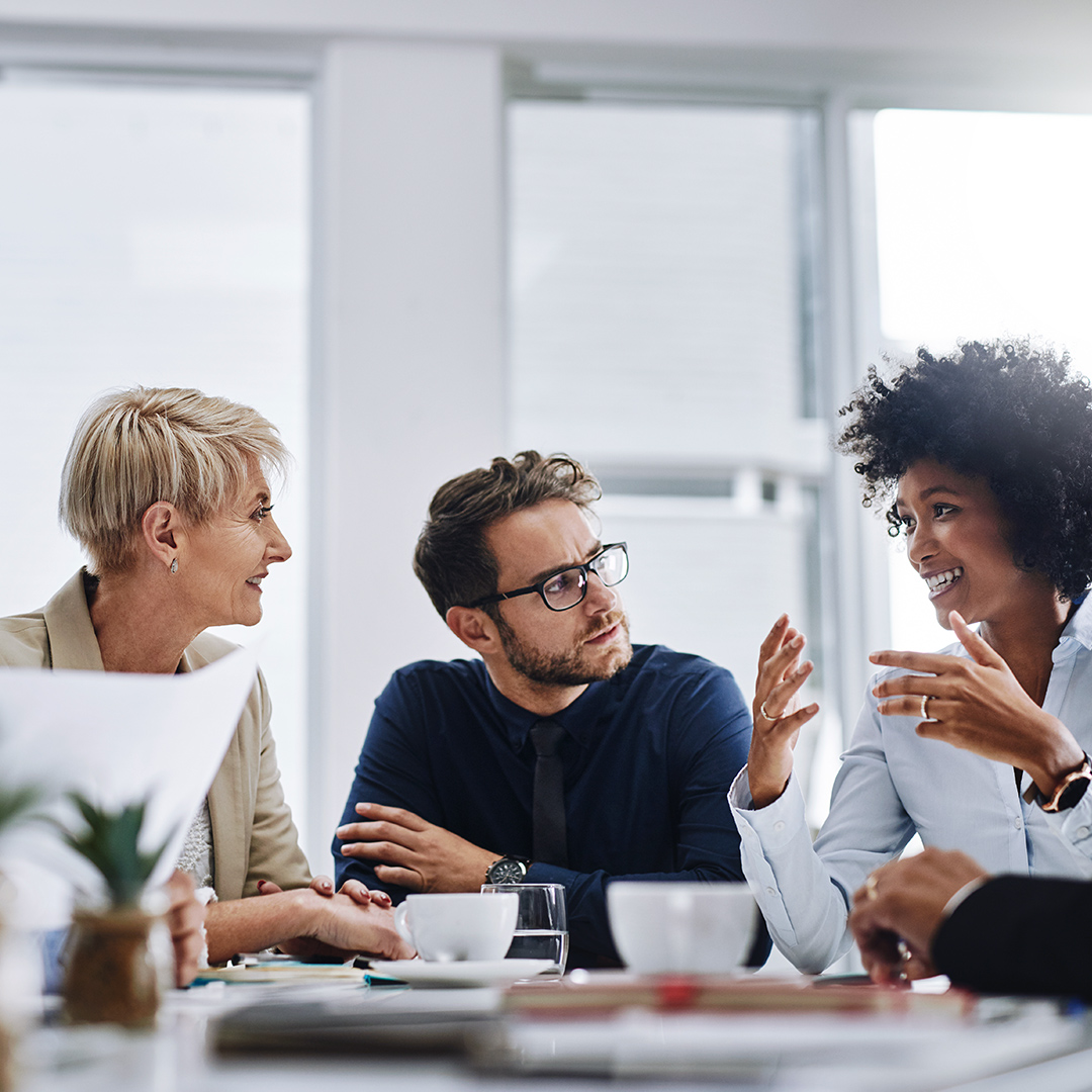 Cuatro empleados están discutiendo juntos en una sala de reuniones.