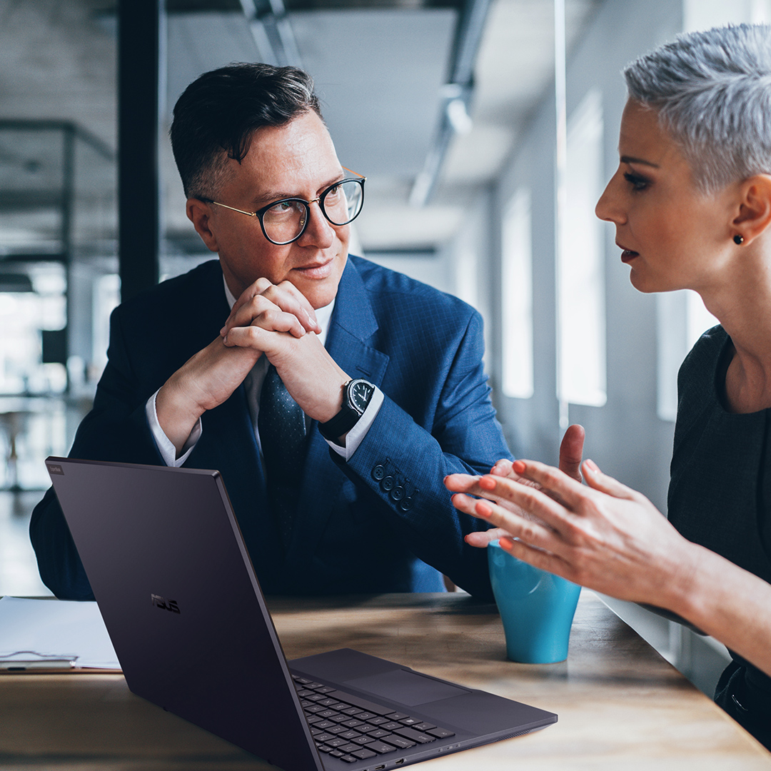 Deux employés avec un ordinateur portable ASUS ont une conversation joviale.