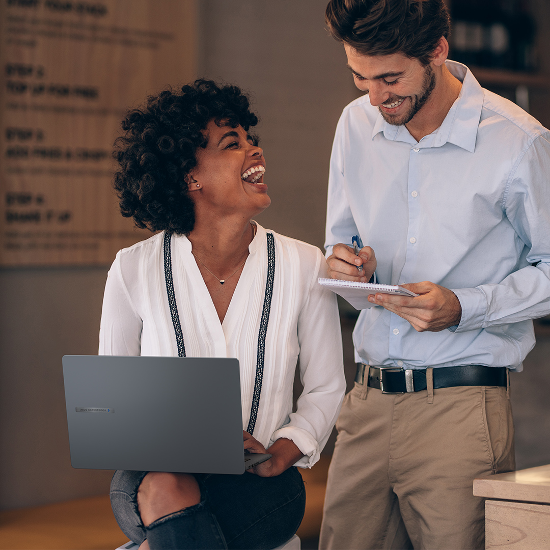 Two empolyees are discussing and laughing together with an ASUS ExpertBook on laps.