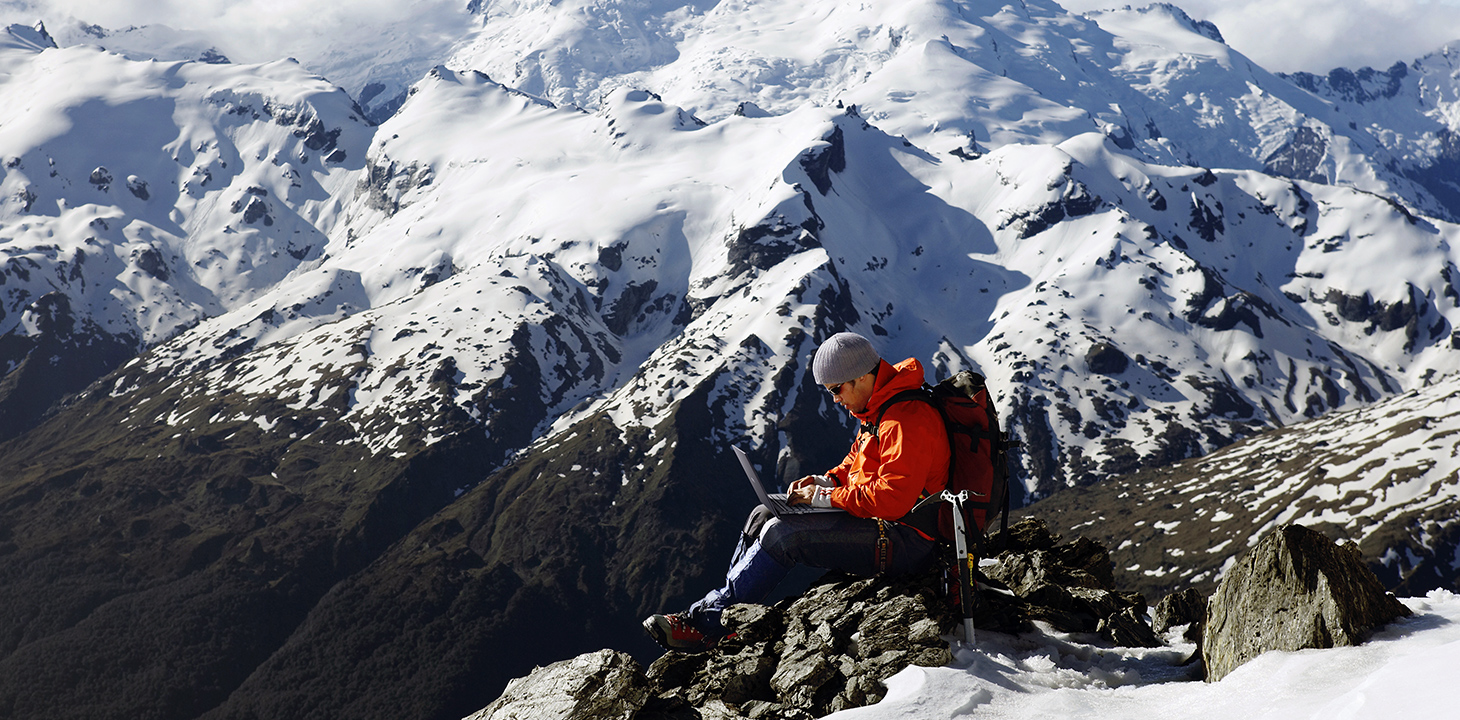 Un homme utilise un ordinateur portable ASUS ExpertBook sur une haute montagne.